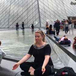 Kvinde mediterer i yogastilling ved Louvre – som en del af yoga.