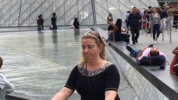 Kvinde mediterer i yogastilling ved Louvre – som en del af yoga.