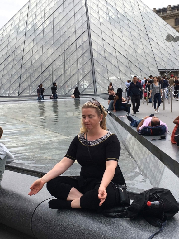 Kvinde mediterer i yogastilling ved Louvre – som en del af yoga.